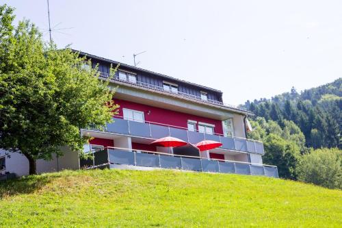 a building with red umbrellas sitting on a hill at Ferienwohnung Streifinger in Freyung