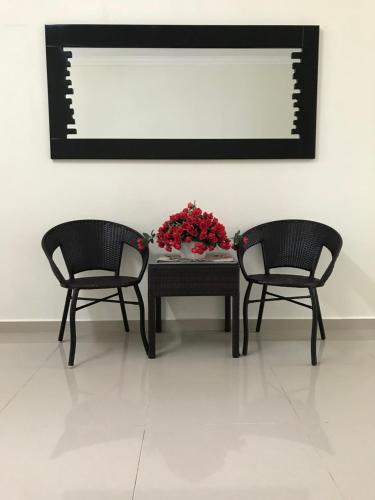 two chairs and a table with a vase of flowers at PATIN GUEST HOUSE @DESA TELOK IRA, TEMERLOH PAHANG in Kampong Paya Kerinau