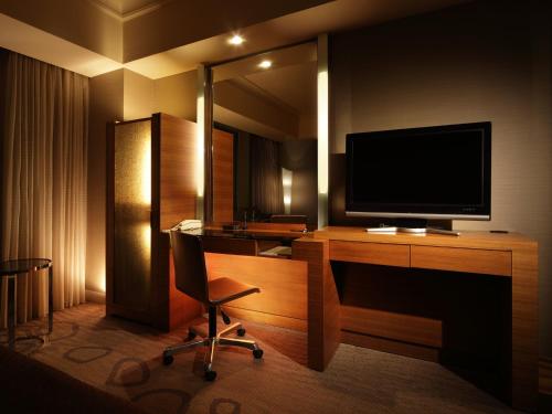 a room with a desk with a television and a chair at Hotel Okura Fukuoka in Fukuoka