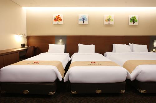 four beds in a hotel room with paintings on the wall at Hotel Skypark Kingstown Dongdaemun in Seoul