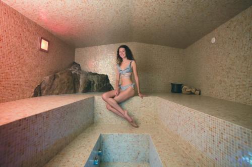 a woman sitting on a ledge in a swimming pool at Casa dei Mulini in Mergozzo