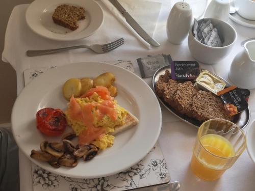 a table with a plate of breakfast foods and a glass of orange juice at Dunagree Bed & Breakfast in Greencastle