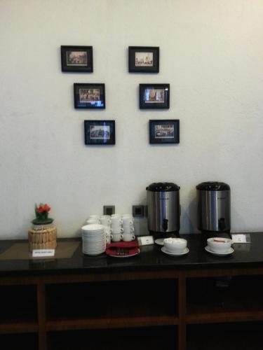 a counter with two coffee pots and plates and pictures on the wall at Hotel Blambangan in Banyuwangi