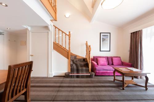 a living room with a purple couch and a table at Mercure Canberra in Canberra