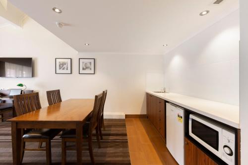 a kitchen and dining room with a table and chairs at Mercure Canberra in Canberra