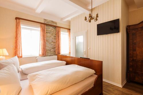 a bedroom with two beds and a television on the wall at Hotel Haus Müller in Marburg an der Lahn