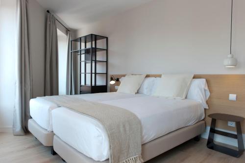 Un dormitorio con una gran cama blanca y una mesa en MH Apartments Central Madrid en Madrid