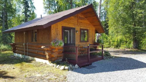 タルキートナにあるTalkeetna Fireweed Cabinsの小さな木造キャビン(森の中のポーチ付)