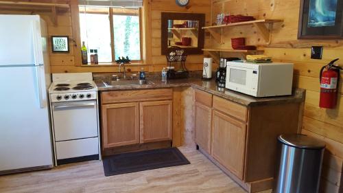 a kitchen with a white refrigerator and a white microwave at Talkeetna Fireweed Cabins in Talkeetna