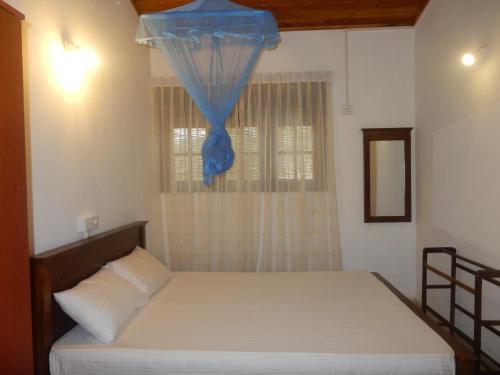 a bedroom with a bed and a window with a blue curtain at Sisanda Residence in Bentota