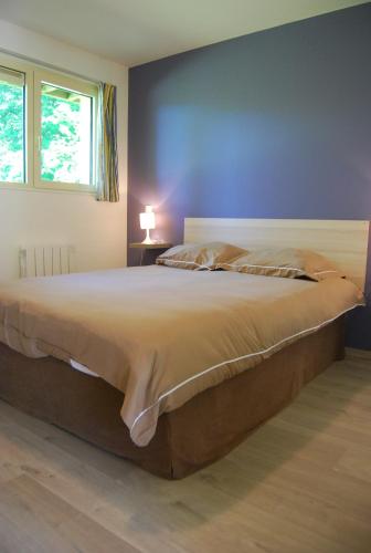 - un grand lit dans une chambre dotée d'un mur bleu dans l'établissement Le Relais du Hibou, à Vittefleur