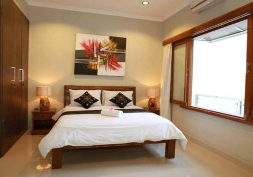 a bedroom with a large bed and a window at Villa Anyelir in Seminyak