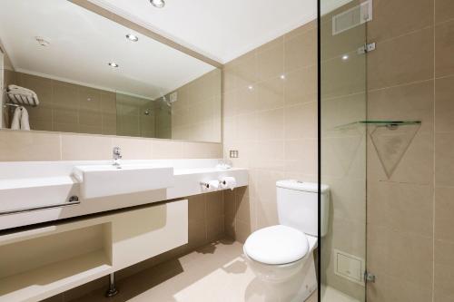 La salle de bains est pourvue de toilettes, d'un lavabo et d'une douche. dans l'établissement Mercure Canberra, à Canberra