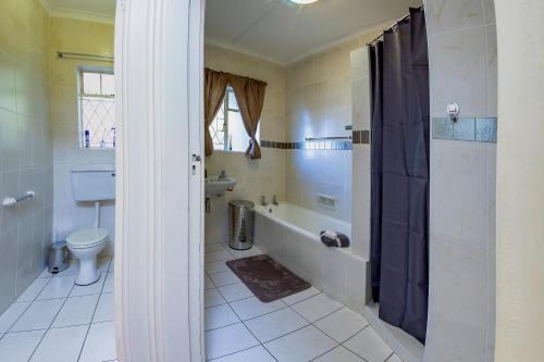 a bathroom with a tub and a toilet and a sink at Munro Suites in Port Elizabeth