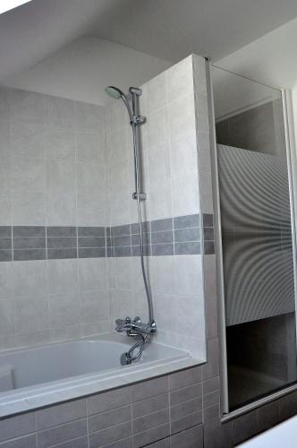 a bathroom with a bath tub with a shower at Maison Roche Blanche in Port Blanc