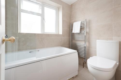 a bathroom with a tub and a toilet and a window at Sea Breeze Cottage with Parking in Brighton & Hove