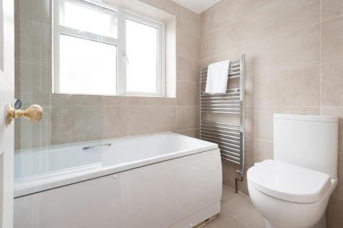 une salle de bain avec baignoire et toilettes et une fenêtre dans l'établissement Sea Breeze Cottage with Parking by MyHolidayLet, à Brighton et Hove