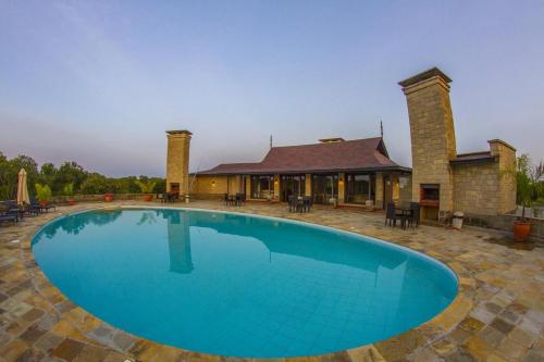a large blue swimming pool in front of a house at Ol Pejeta Holiday Villas in Nanyuki