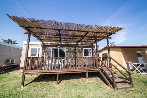 a wooden pergola with a deck in a yard at Camping Ermosa in Posada