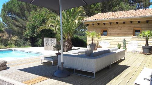 um pátio com um sofá e um guarda-sol ao lado de uma piscina em La Belle Landaise 1809 Gîte Arridoulet 1 em Peyrehorade