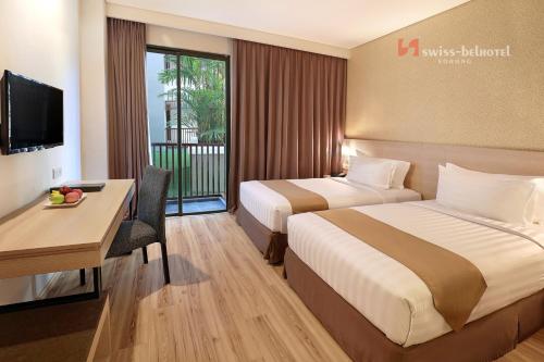 a hotel room with two beds and a desk at Swiss-Belhotel Sorong in Sorong