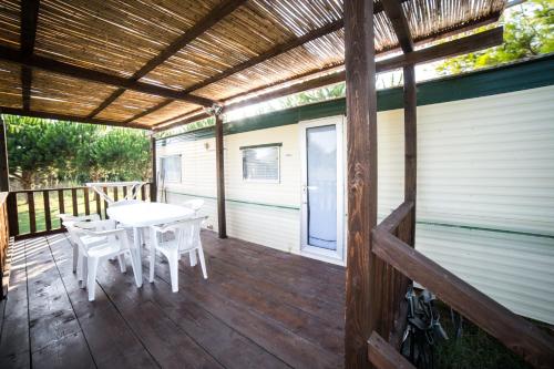 a wooden deck with a table and chairs on it at Camping Ermosa in Posada