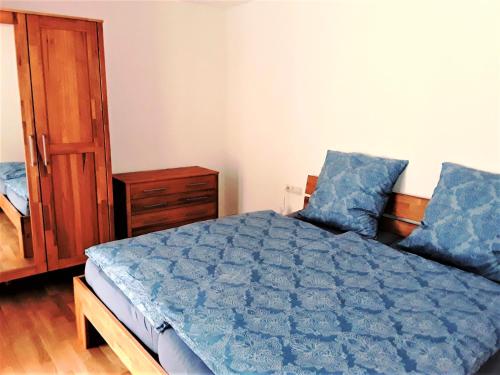 a bedroom with a blue bed and a wooden cabinet at Ferienwohnung Enzblick in Bad Wildbad