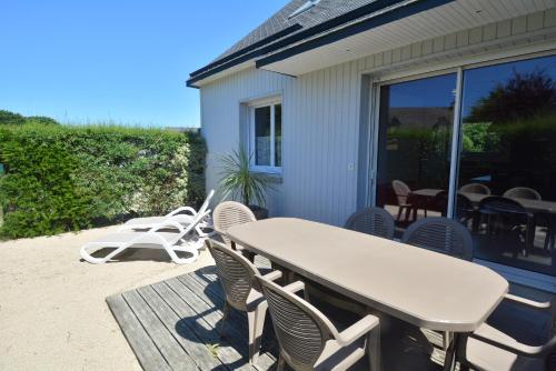een terras met een tafel en stoelen op een dek bij Roche Blanche 1 in Saint-Lunaire