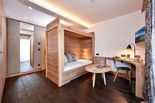 a room with a bed and a desk and a table at Staudacherhof in Garmisch-Partenkirchen I Blick aufs Zugspitzmassiv I einzigartige Bayurvida Küche in Garmisch-Partenkirchen