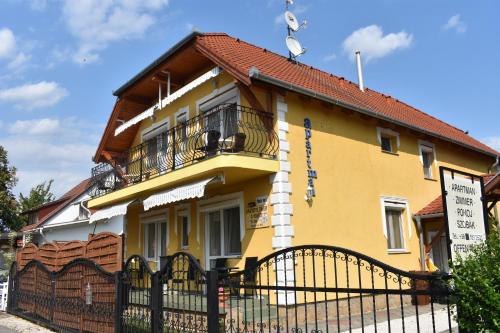 a yellow house with a fence in front of it at Villa Bella Apartman in Bük
