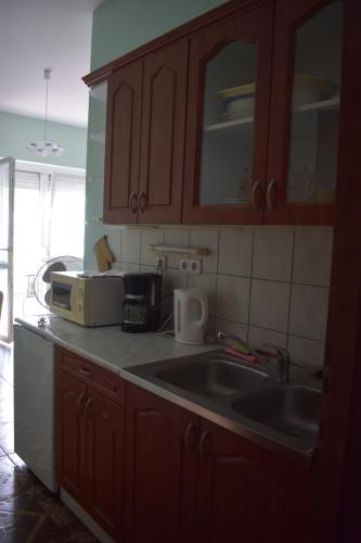 a kitchen with wooden cabinets and a sink at Villa Bella Apartman in Bük