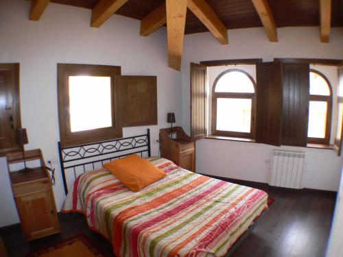 a bedroom with a bed and two windows at 1g CASA DE LOS FERNANDEZ RAJO in Orihuela del Tremedal