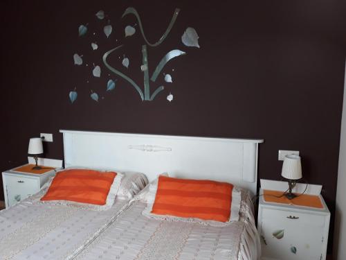 a bedroom with a white bed with two orange pillows at Casa La Escuela in Tuilla