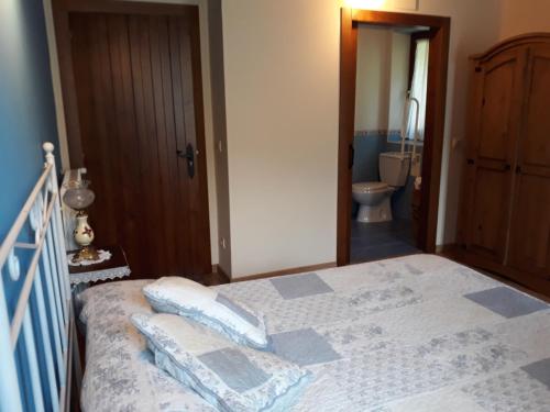 a bedroom with a bed and a bathroom with a toilet at Casa La Escuela in Tuilla