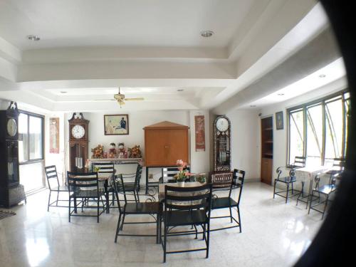 a dining room with chairs and a table and clocks at Sathitsit Mansion in Bangkok