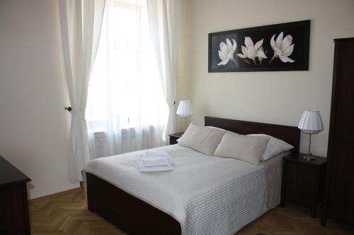 a bedroom with a bed with white sheets and a window at Place 4 You Apartments in Krakow