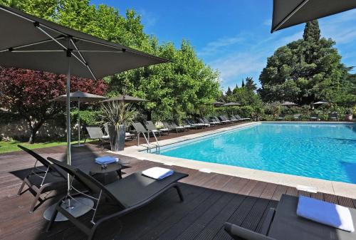 a swimming pool with chairs and umbrellas next to a pool at Le Prieure in Villeneuve-lès-Avignon