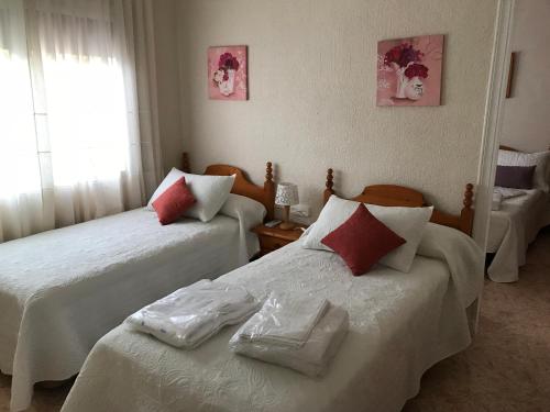 a bedroom with two beds with red and white pillows at Casa con terraza in Dehesa de Campoamor