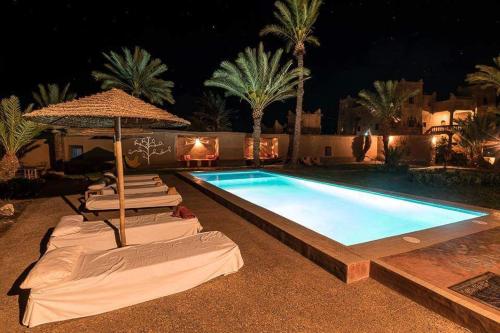a swimming pool with lounge chairs and an umbrella at Dar Es Salam in Skoura