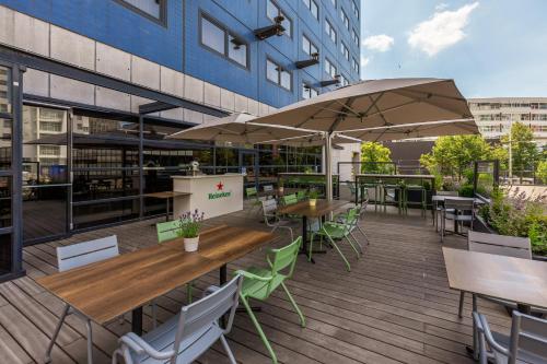 een patio met tafels, stoelen en parasols bij Mercure Hotel Den Haag Central in Den Haag