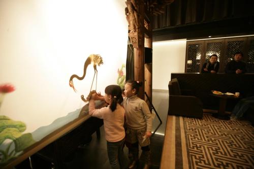 a man and a woman looking at a lizard on a wall at Beijing Shichahai Shadow Art Performance Courtyard in Beijing