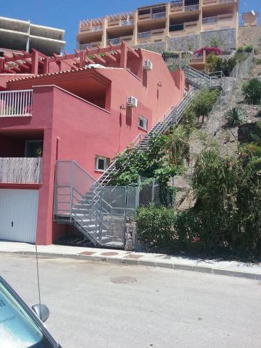a red building with a staircase next to a building at El Peñoncillo in Torrox