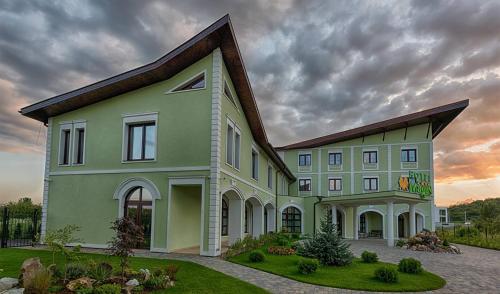 a large green building with a sky at Magus Hotel in Baia Mare