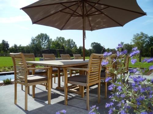 a wooden table with chairs and an umbrella at B&B Welcome Home in Laakdal