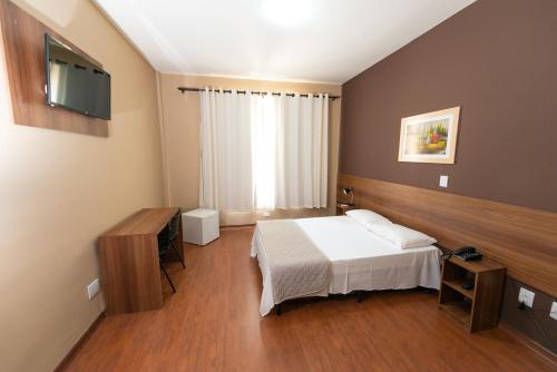 um quarto de hotel com uma cama e uma televisão em Hotel Regional JF em Juiz de Fora
