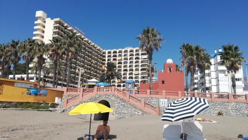 een persoon die onder een parasol op het strand zit bij Estudio playa Benalmadena in Benalmádena