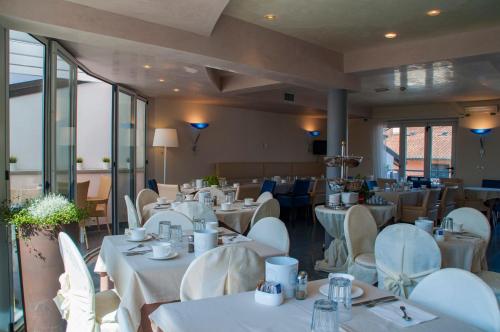 una sala da pranzo con tavoli bianchi e sedie bianche di Hotel Regina a Grado