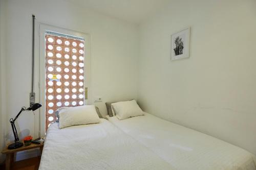 a white bedroom with a bed and a window at Beachfront Resort Apartment in Castelldefels