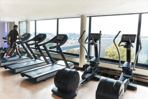 un grupo de cintas de correr en un gimnasio con ventanas en Steigenberger Airport Hotel Frankfurt, en Frankfurt