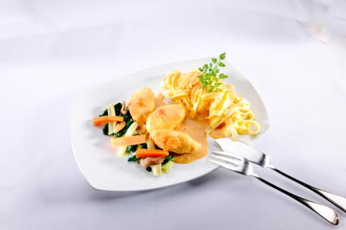 a plate of food with pasta and vegetables on a table at Hotel Restaurant L'Ami Fritz in Ottrott